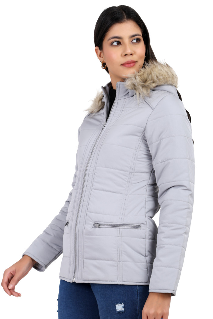 A woman in a standing side pose, wearing Trufit’s grey Matte Quilted Jacket with Horizontal Pockets, zip closure, a removable hood and blue jeans.